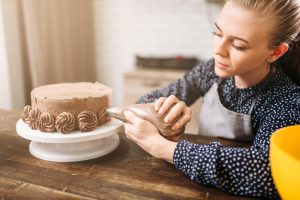 A young woman decorates a cake with an icing bag