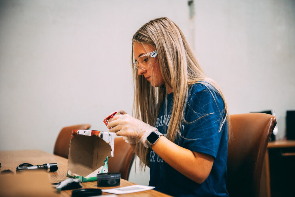 criminal justice student dusts a box for fingerprints.