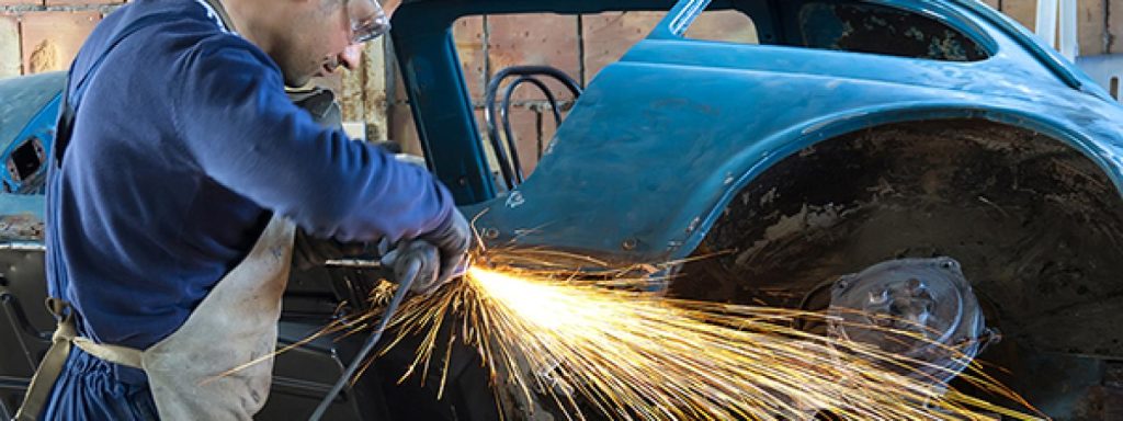 auto collision technology student uses grinder on car panel