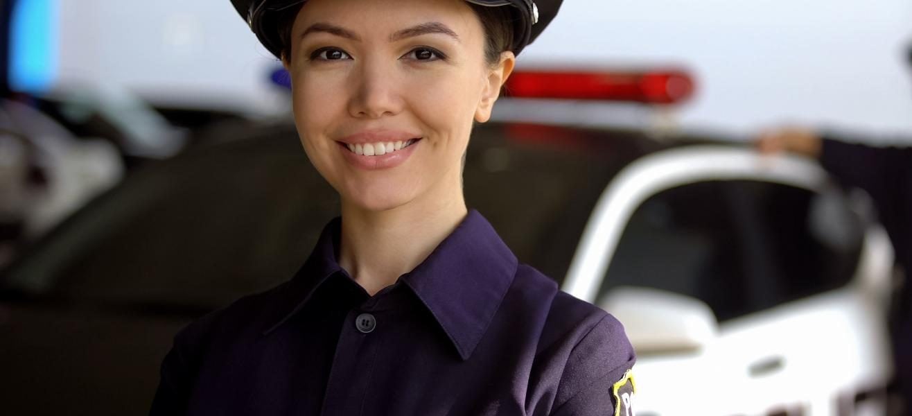 A female officer in front of patrol car poses for a photo