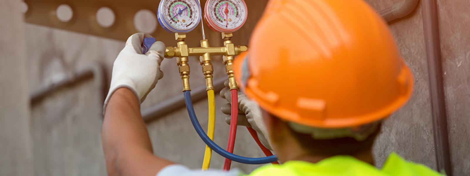 heating ventilation air conditioning refrigeration technician reads a manifold gauge