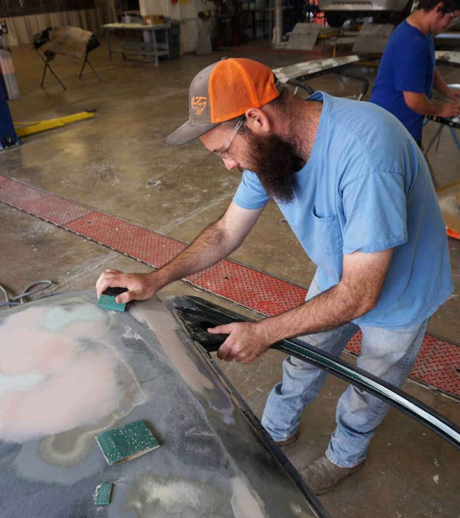 Student sands down a car panel