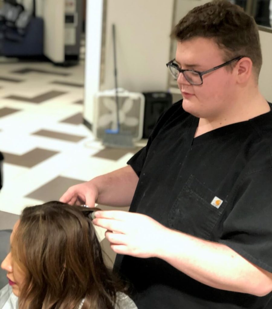 Male student trims a person's hair in Cosmetology