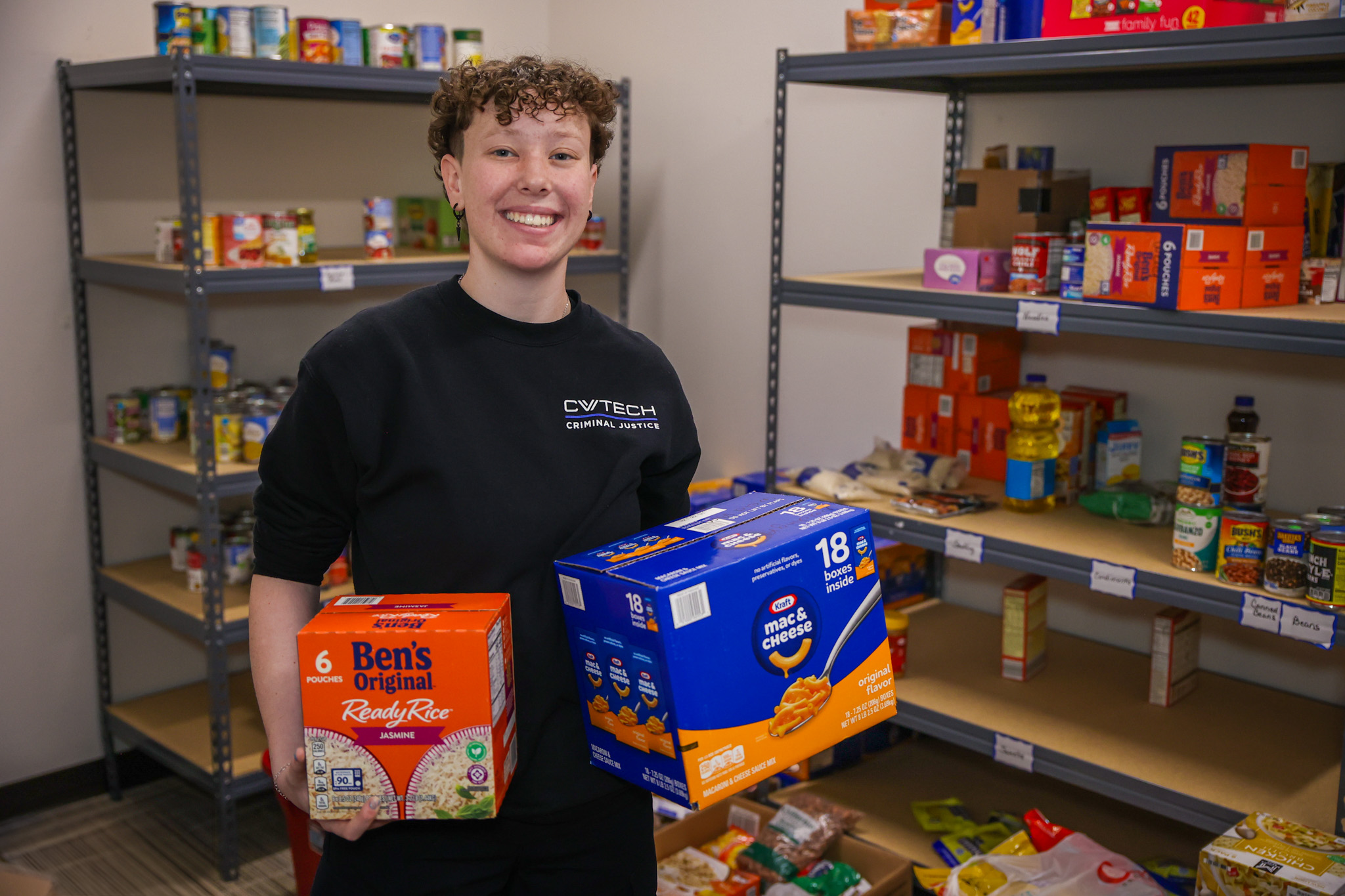 CV Tech student holding multi-packs of rice and mac and cheese.