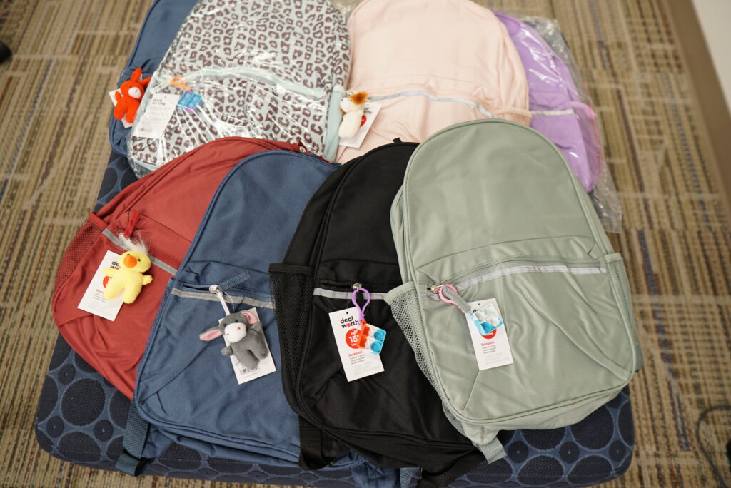 Seven colorful, new backpacks are fanned out in a straight line on two rows.