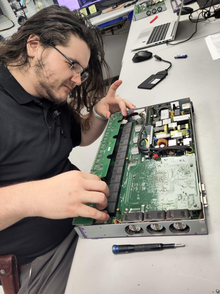 A man tinkers with the insides of a computer at his desk.