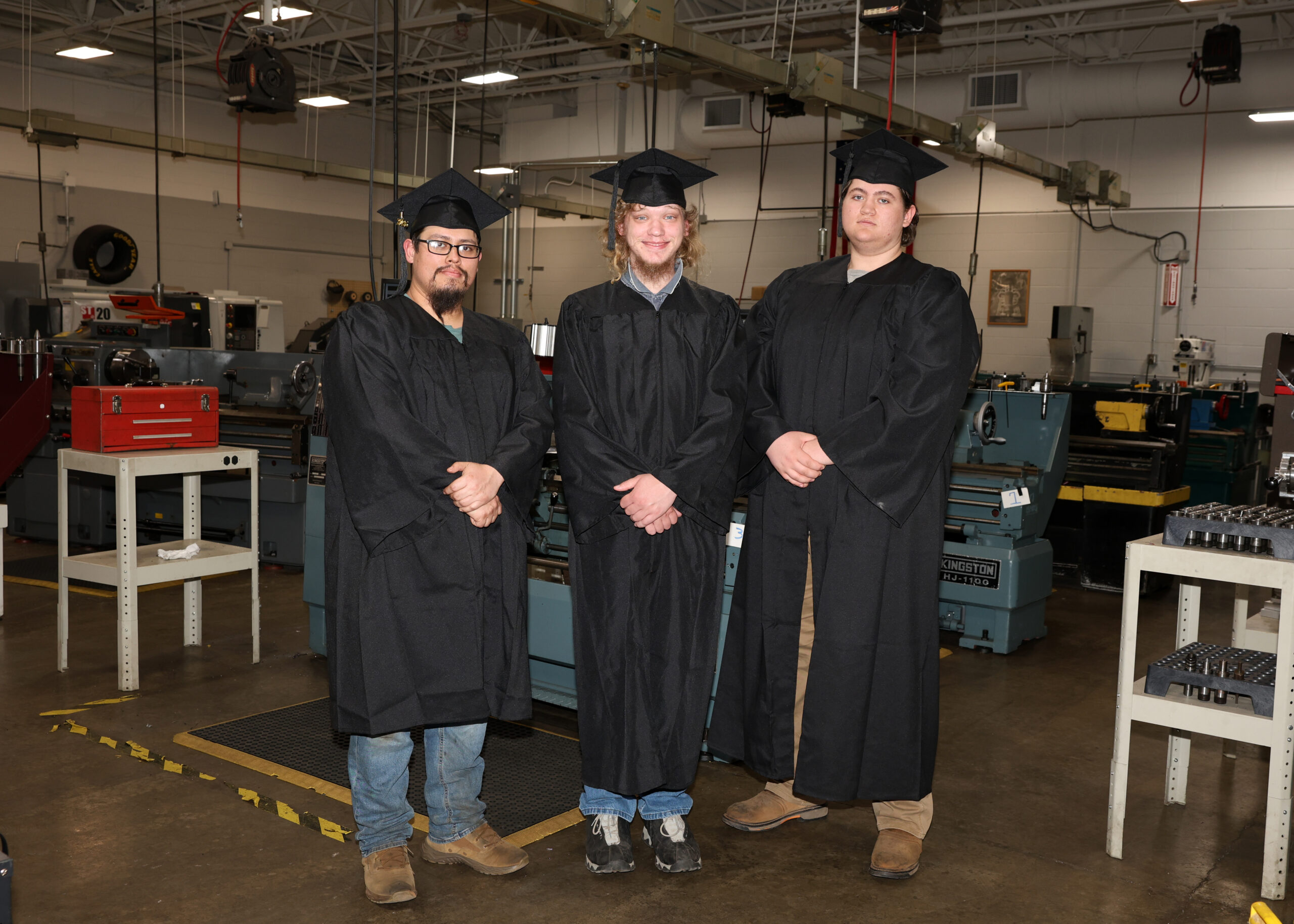 precision machining students in caps and gowns in their shop.