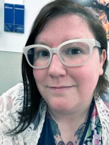 A close-up photo of a young lady smiling with white-rim glasses.