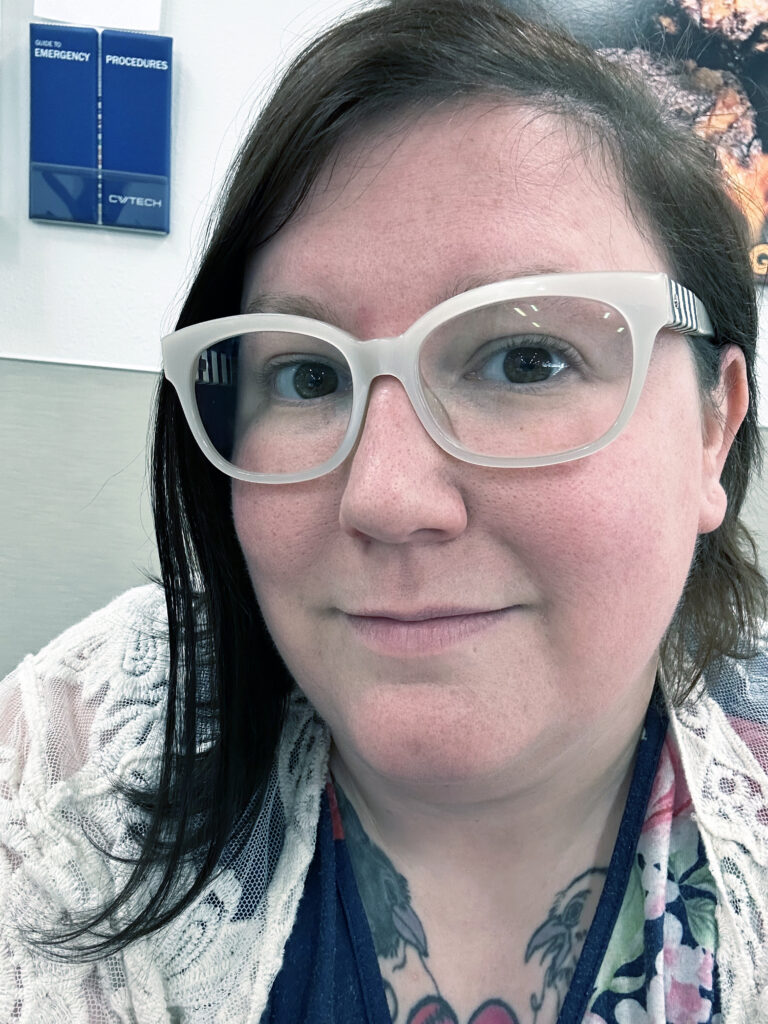 A close-up photo of a young lady smiling with white-rim glasses.