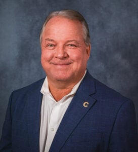 Jim Cowan, board of education member in navy coat with white collared shirt beneath.