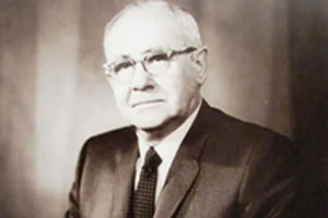 This is a black and white photo of an older gentleman wearing a suit and eyeglasses.